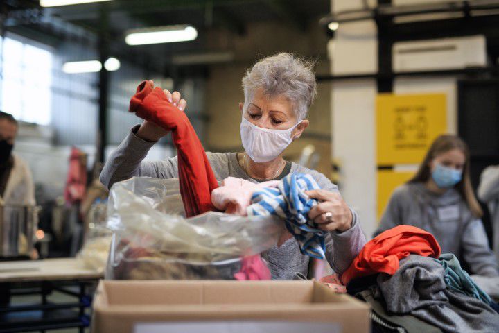 Alte Frau die Spenden aus einem Altkleidercontainer organisiert