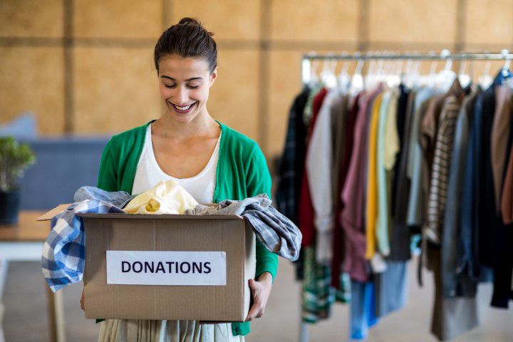 Junge Frau mit einer Kiste mit Spenden aus dem Altkleidercontainer