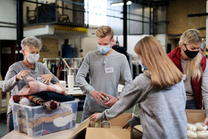 Mitarbeiter einer Wohltatigkeitsorganisation beim Sortieren von Altkleiderspenden in Containern