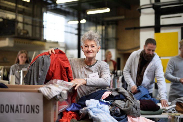Lachelnde Frau beim Sortieren von gespendeter Kleidung